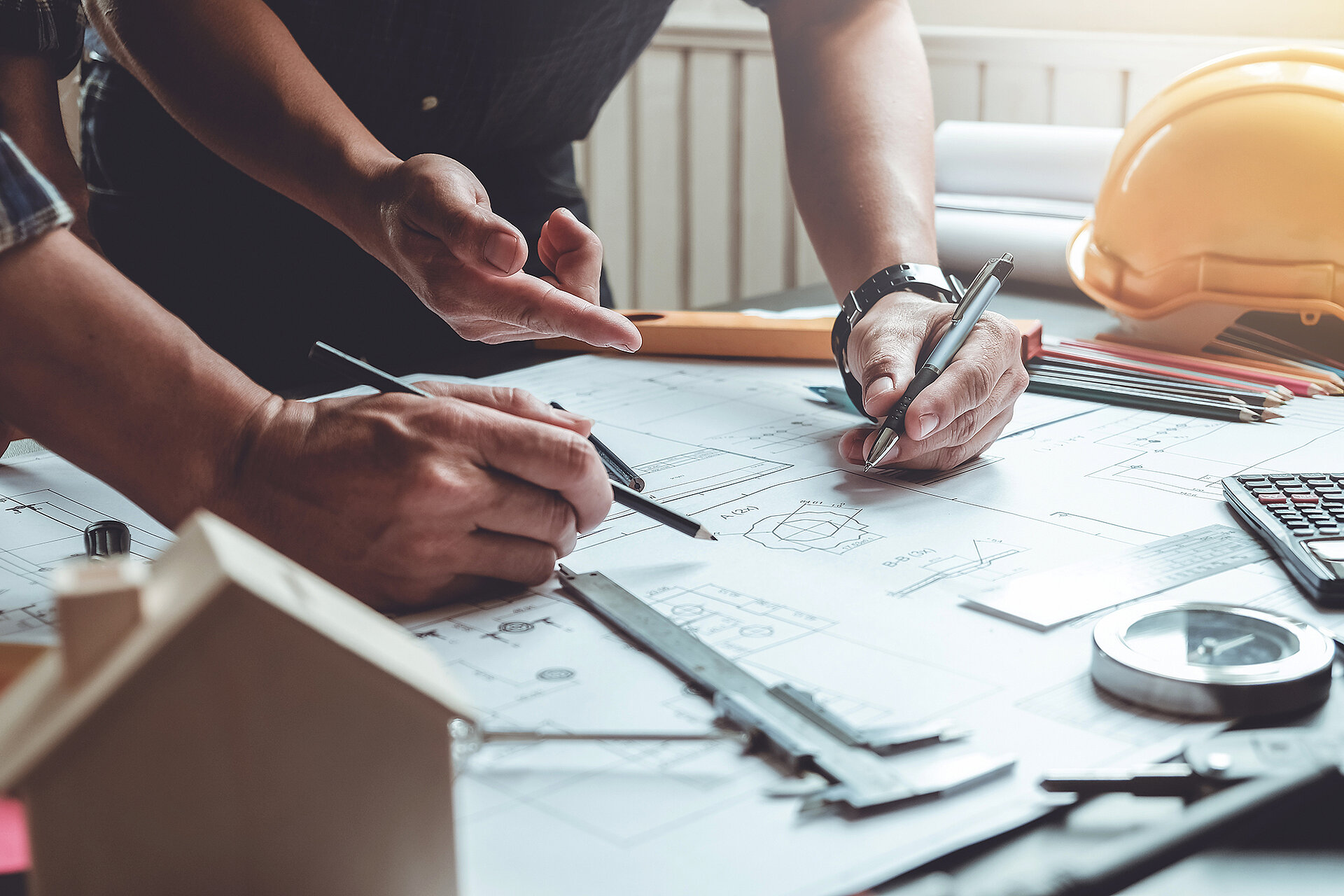 2 Architekten planen etwas an einem Schreibtisch und haben einen Stift in der Hand