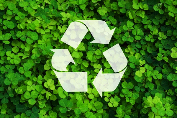 Recycling sign, green leaves in background