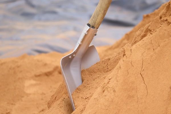 A shovel placed in a pile of sand