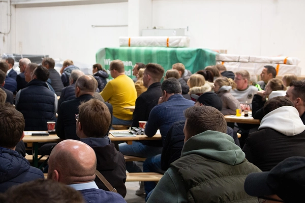 Die Belegschaft der DCG beim Kick-off in der Produktionshalle sitzend
