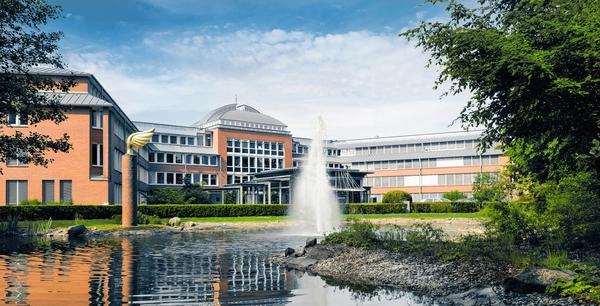 Gebäude Treuhand. Davor ein Springbrunnen, eine Wiese und eine Hecke