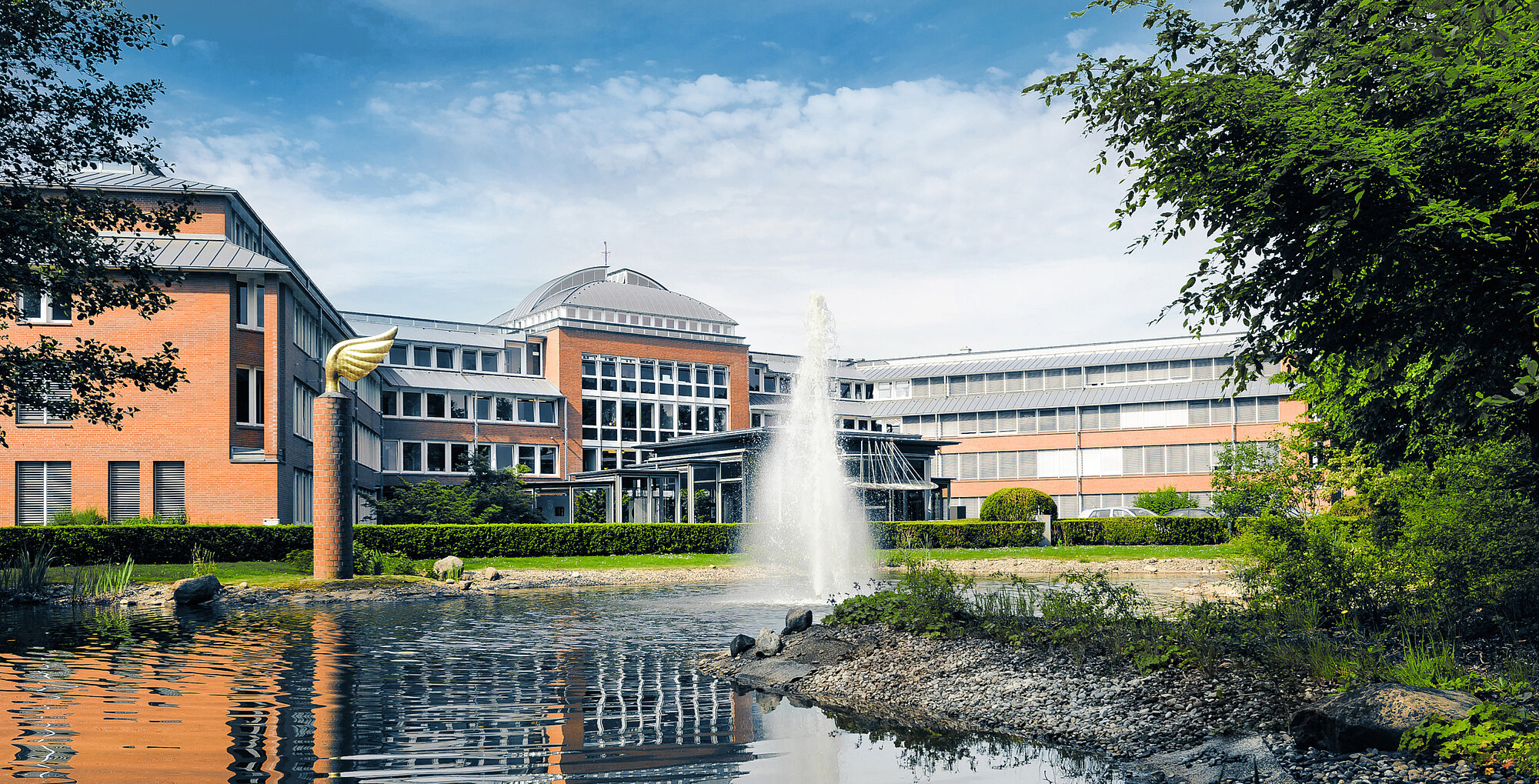 Gebäude Treuhand. Davor ein Springbrunnen, eine Wiese und eine Hecke