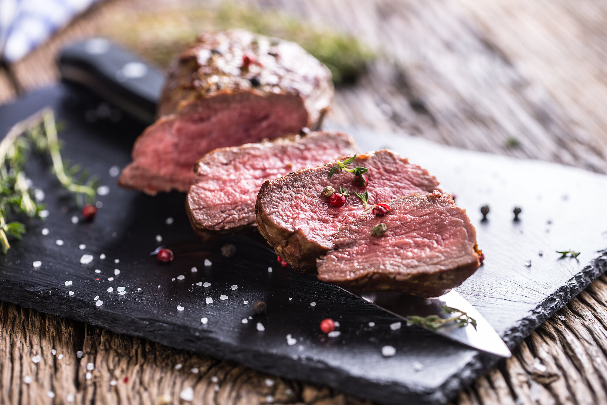Medium gebratenes Rindfleisch auf einem schwarzen Brett mit Salz, Pfeffer und Gewürzen serviert