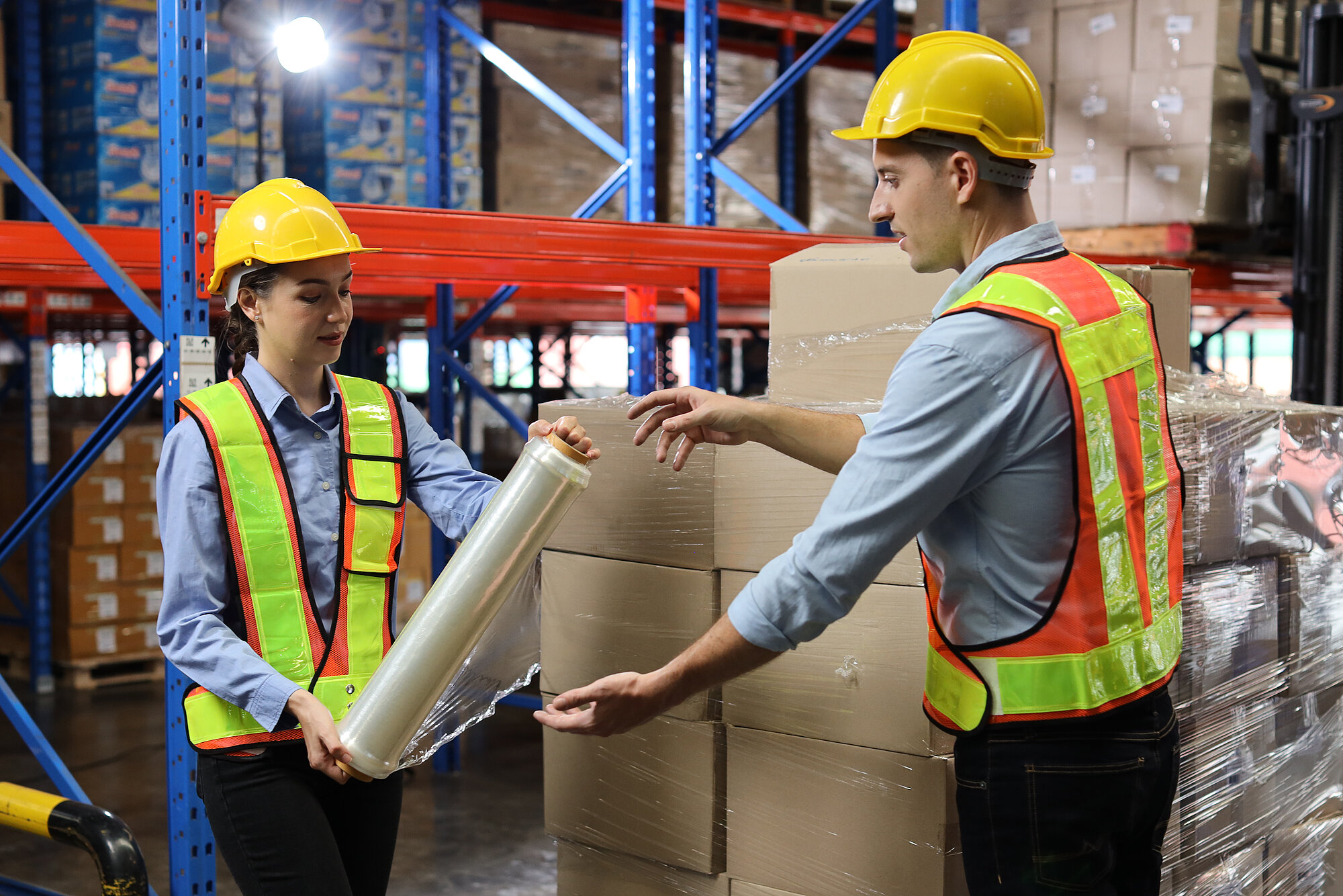 Mann und Frau in Arbeitskleidung halten Verpackungen in der Hand