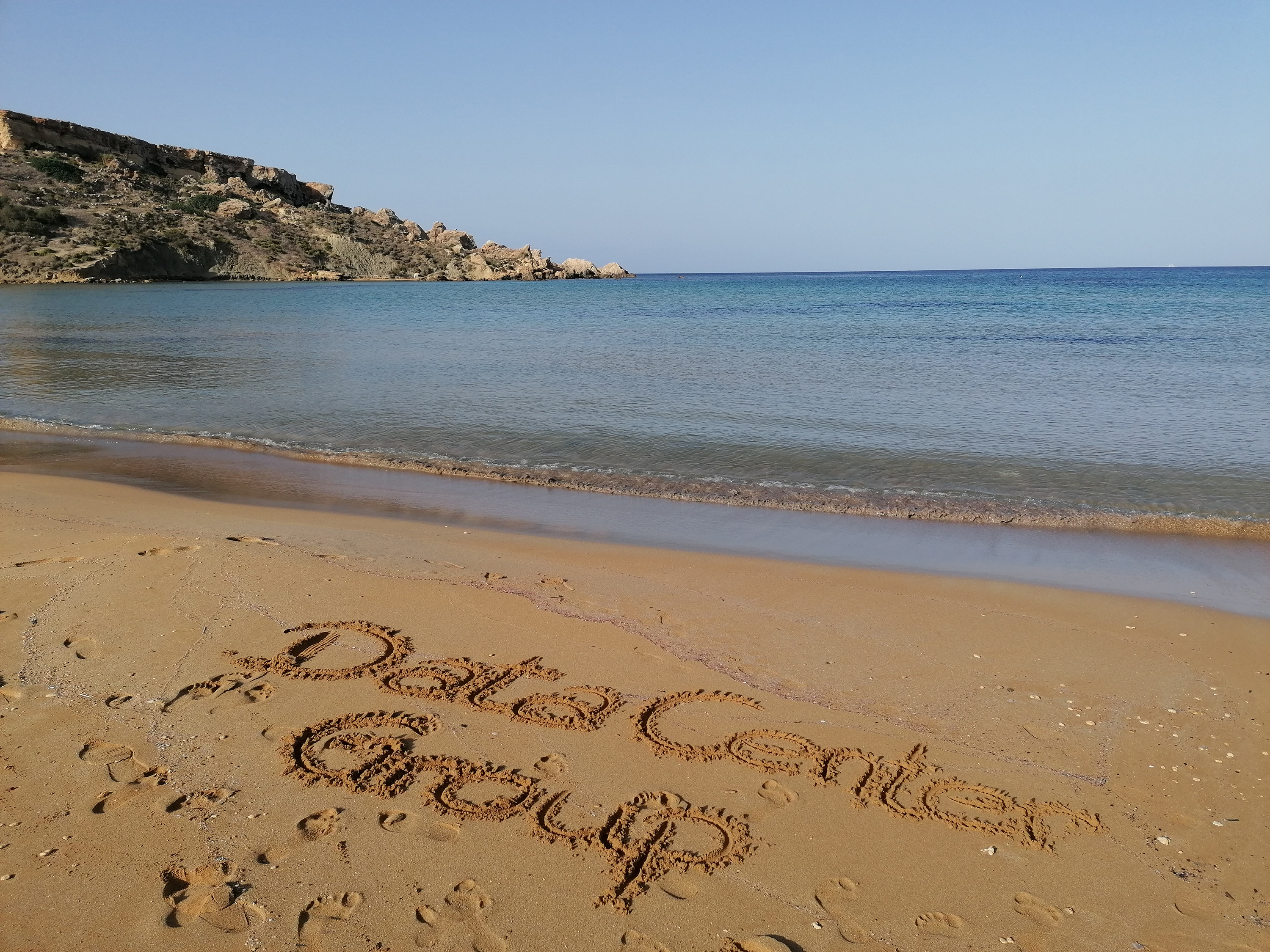 Sandstrand auf Malta, in dem Data Center Group im Sand geschrieben steht
