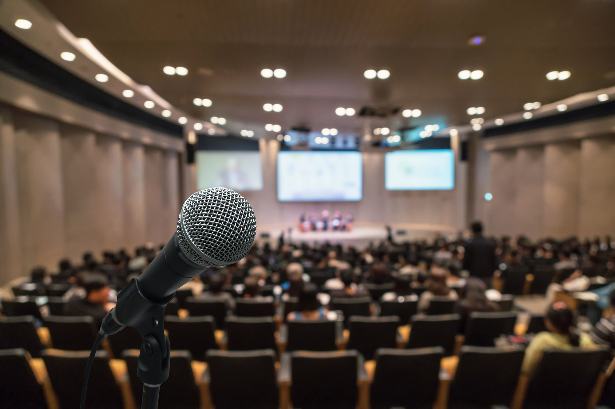 Ein Saal voller Menschen, im Vordergrund ein Mikrofone 