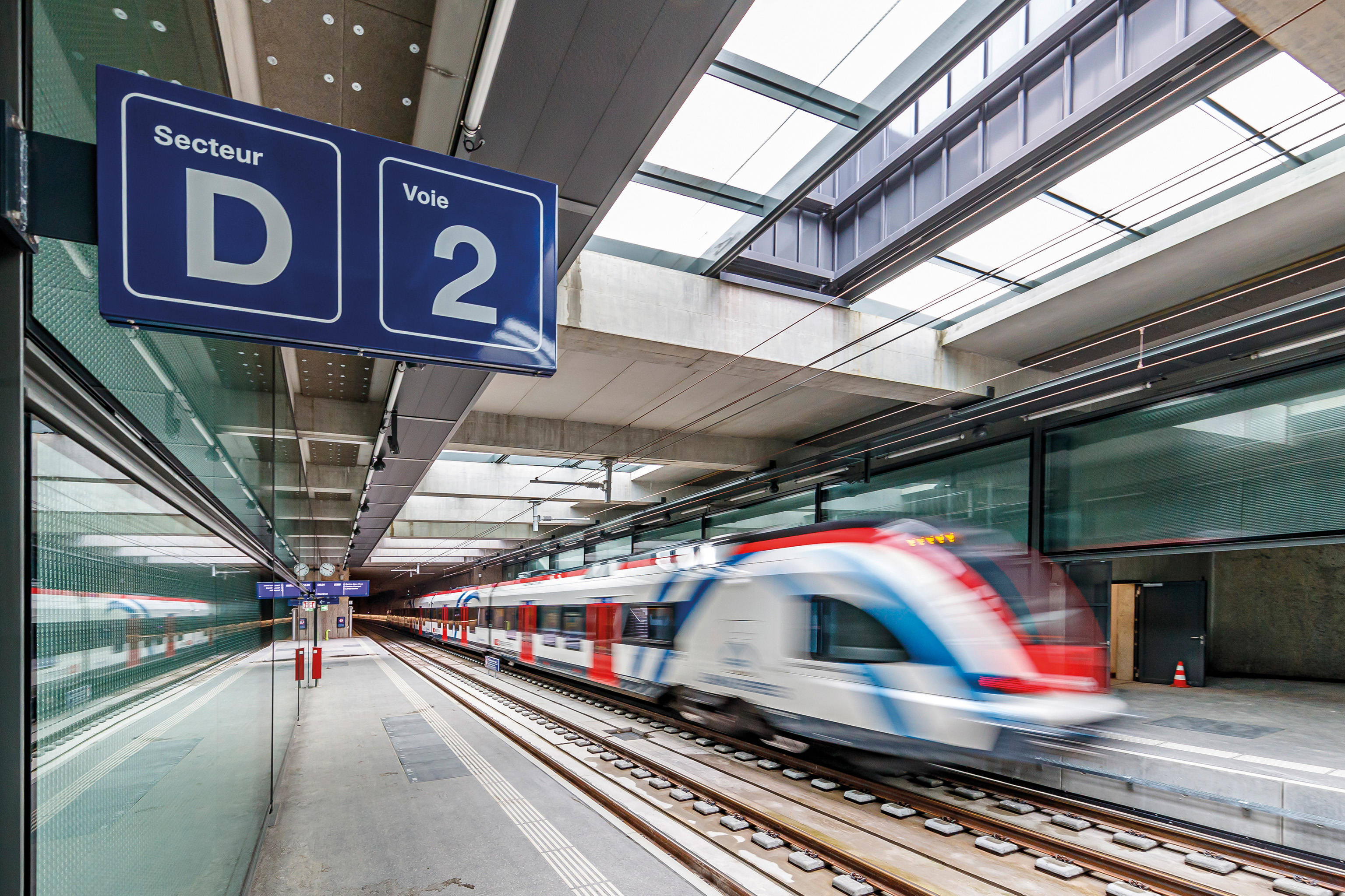 Einfahrender weißer Zug, der durch einen Bahnhof fährt