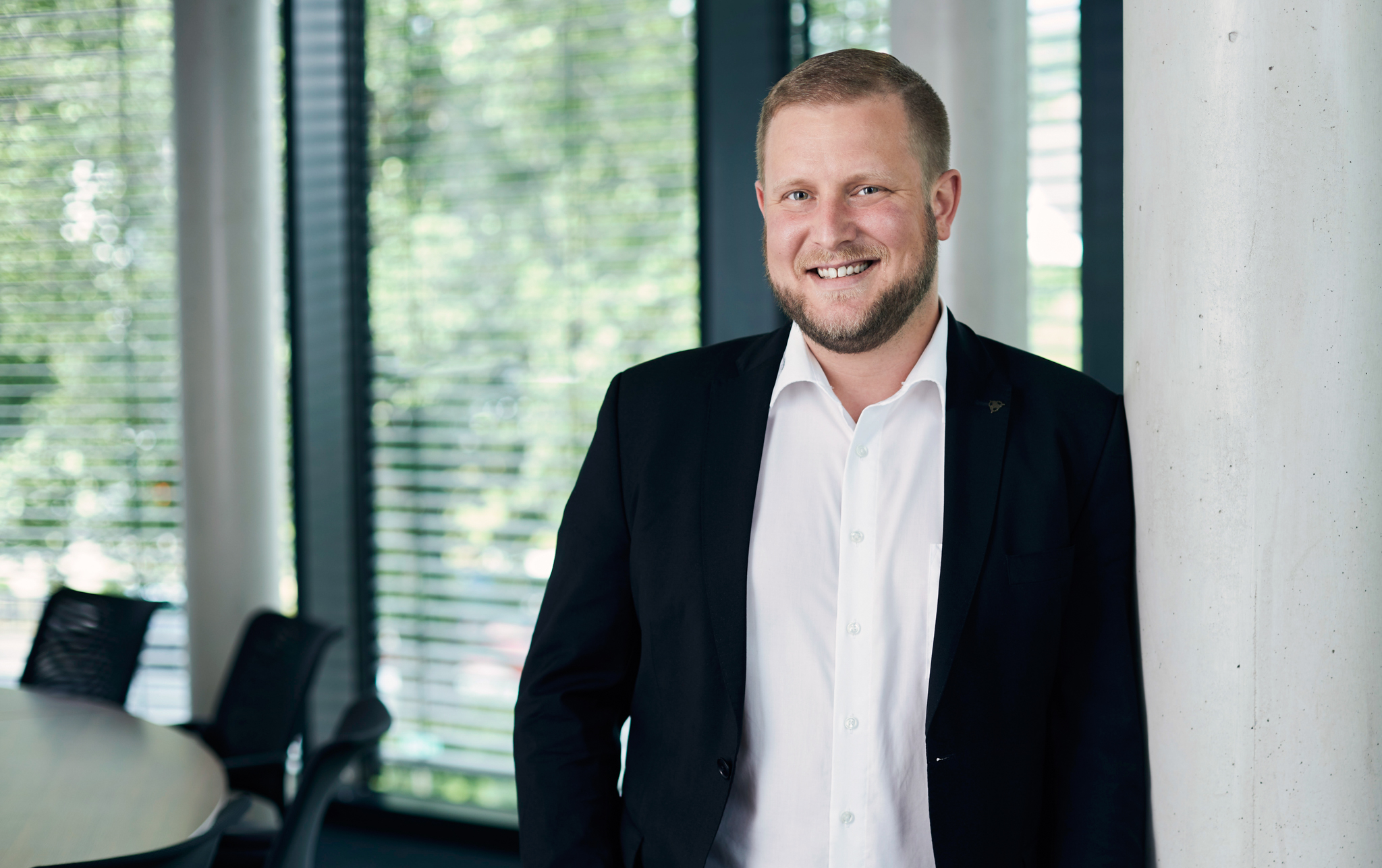 Picture of Florian Hammer, standing, laughing in a shirt